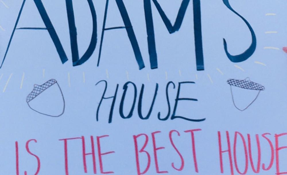 A picture of a white poster with "Adams House is the Best House" written on it.