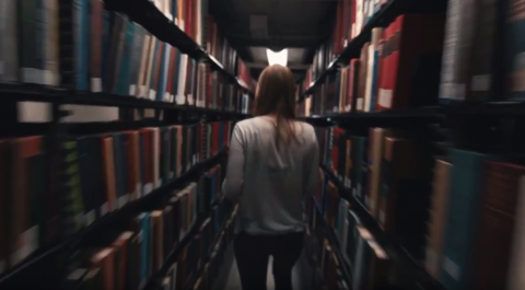 Student walking through library stacks