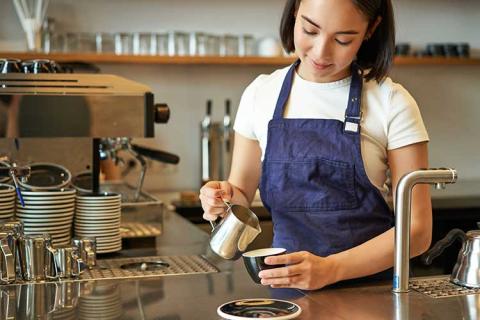 female working in a coffee shop. Shown pouring coffee