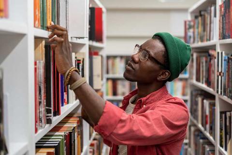 upclose of student looking at books on a shelf in the library