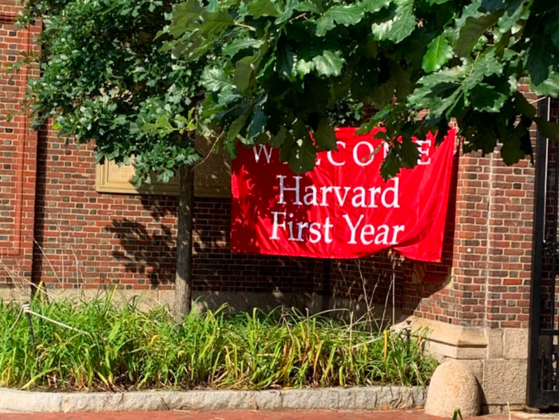 A picture of a red banner saying "Welcome Harvard First Year" in front of a brick wall