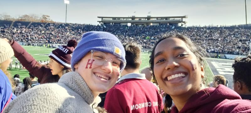 Merlin and Julia smiling in front of Yale's football field 
