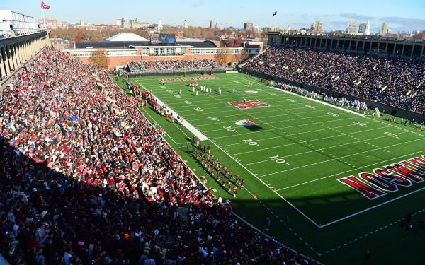 An upward view of Harvard Stadium filled with fans and football action on the field.
